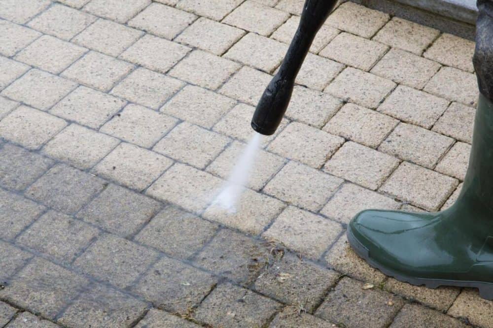 a power washing cleaning a brick patio