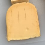 a chunk of smoked gouda cheese on a white cutting board