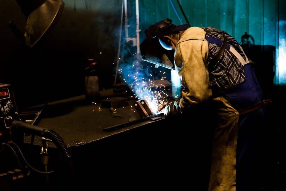 a welder creating and joining peices of an oil tank smoker he has built