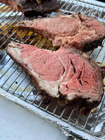 slices of prime rib on a wire rack set over an aluminum foil covered baking sheet