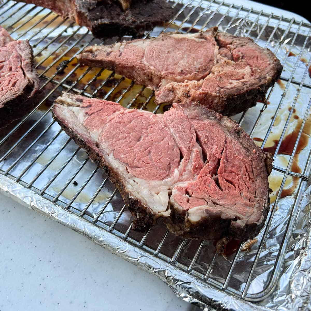 slices of prime rib on a wire rack set over an aluminum foil covered baking sheet