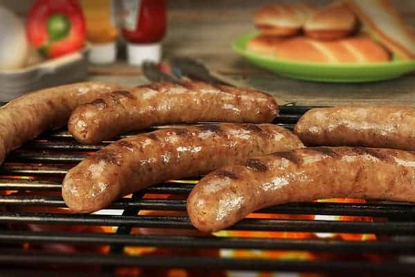 brats grilling on a propane grill