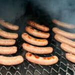 bratwurst smoking on the grates of a pellet grill