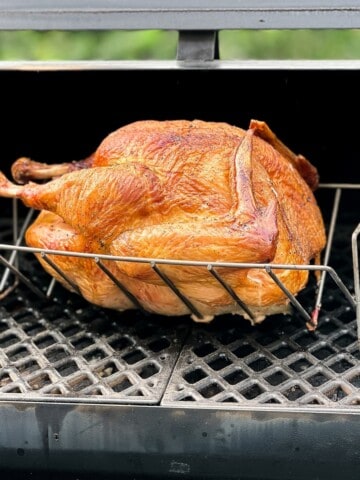 turkey in a V shaped rack smoking on a pellet grill