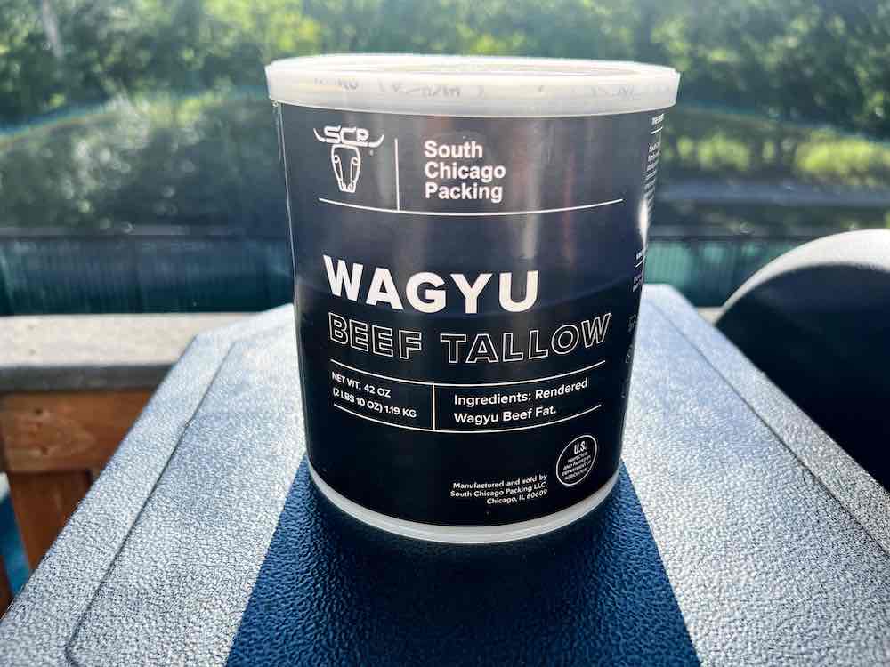 container of Wagyu beef tallow sitting on a pit boss pellet grill