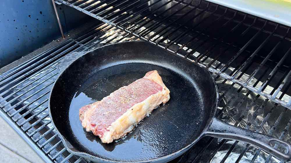 steak in cast iron on pellet grill over indirect heat