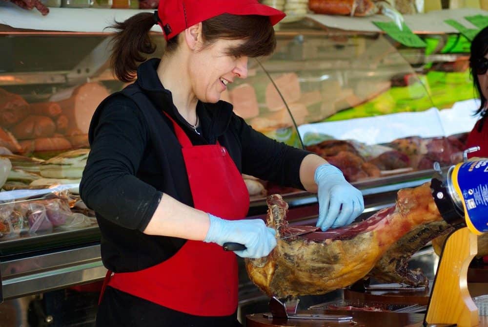 a butcher frenching the bone of a raw ham