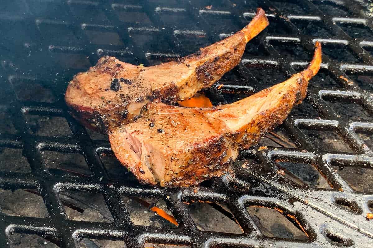 two lamb chops searing on the grates of a pellet grill 