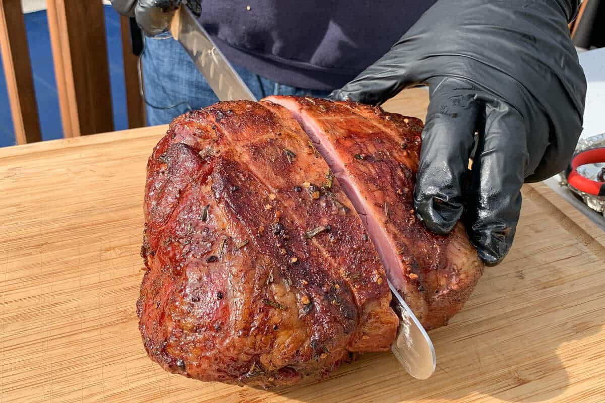 slicing through a leg of lamb with a meat slicing knife