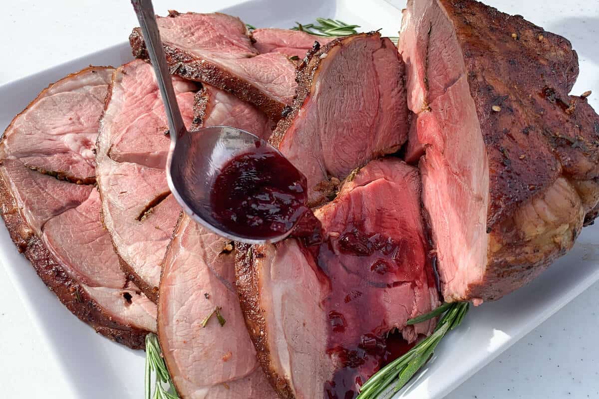 drizzling a red wine sauce over the slices of leg of lamb