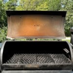 an open pellet grill with rust on the inside lid and front