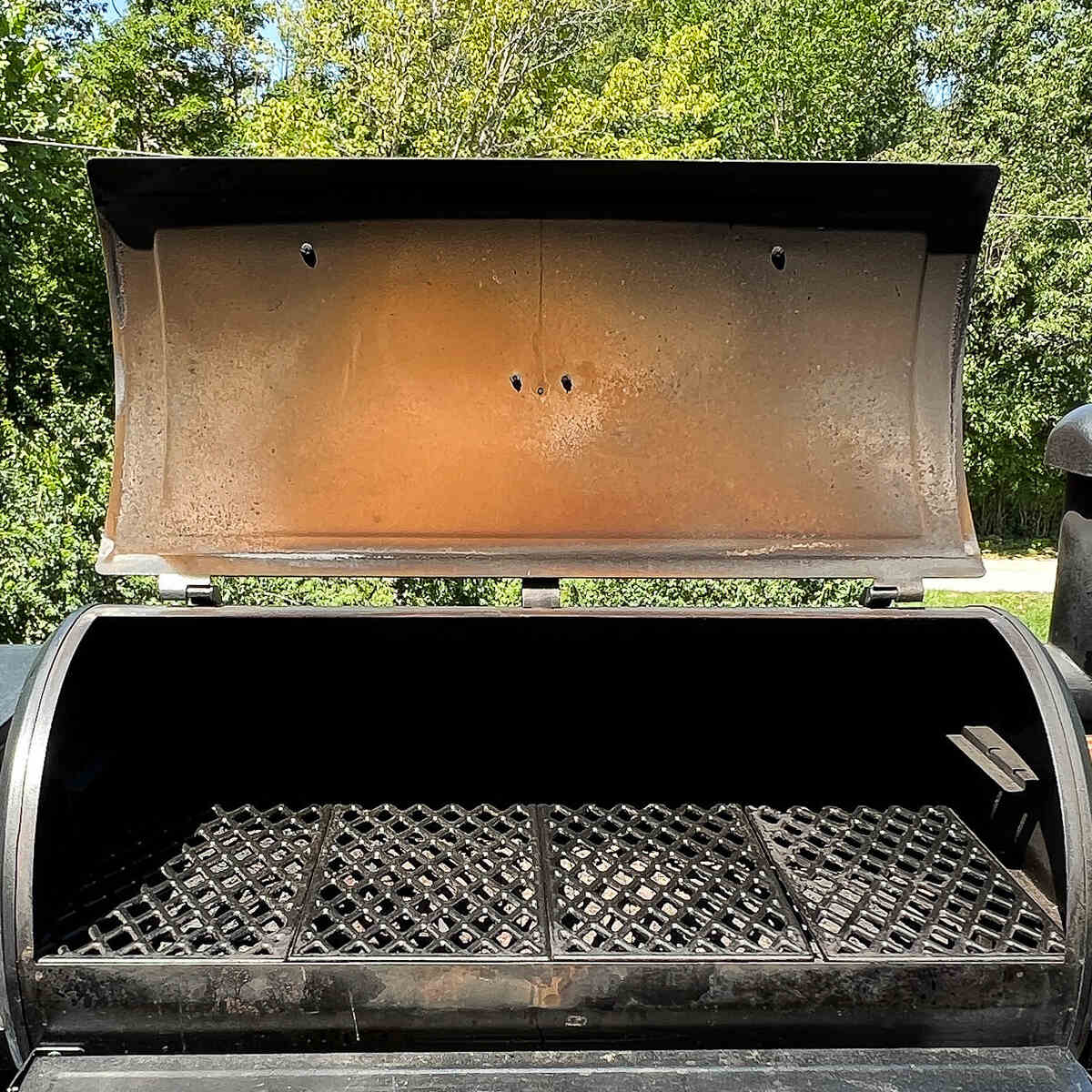 an open pellet grill with rust on the inside lid and front