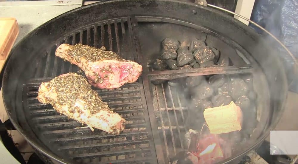 lamb shanks smoking on a charcoal grill