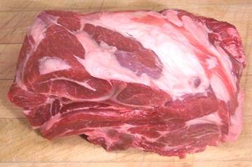 a raw lamb shoulder on a cutting board