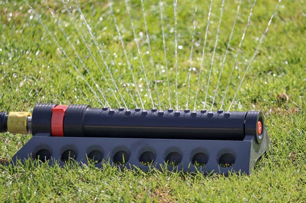 a sprinkler watering a green lawn in the summer