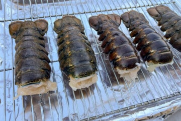 intact lobster tails on a wire rack set over a baking sheet