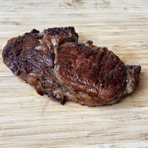 a smoked and seared ribeye steak on a wooden cutting board