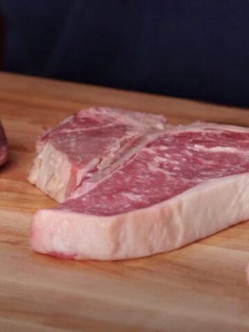 a cutting board comparing a filet mignon with a new york strip steak