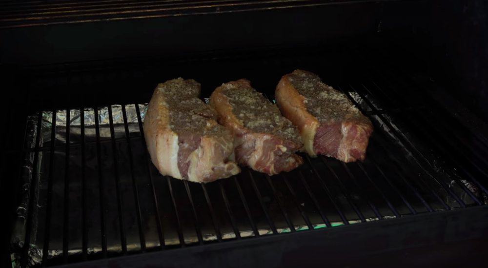 more ribeye steaks being smoked on a smoker