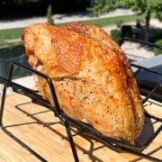 turkey breast cooked on a pellet grill on a metal rack set over a cutting board