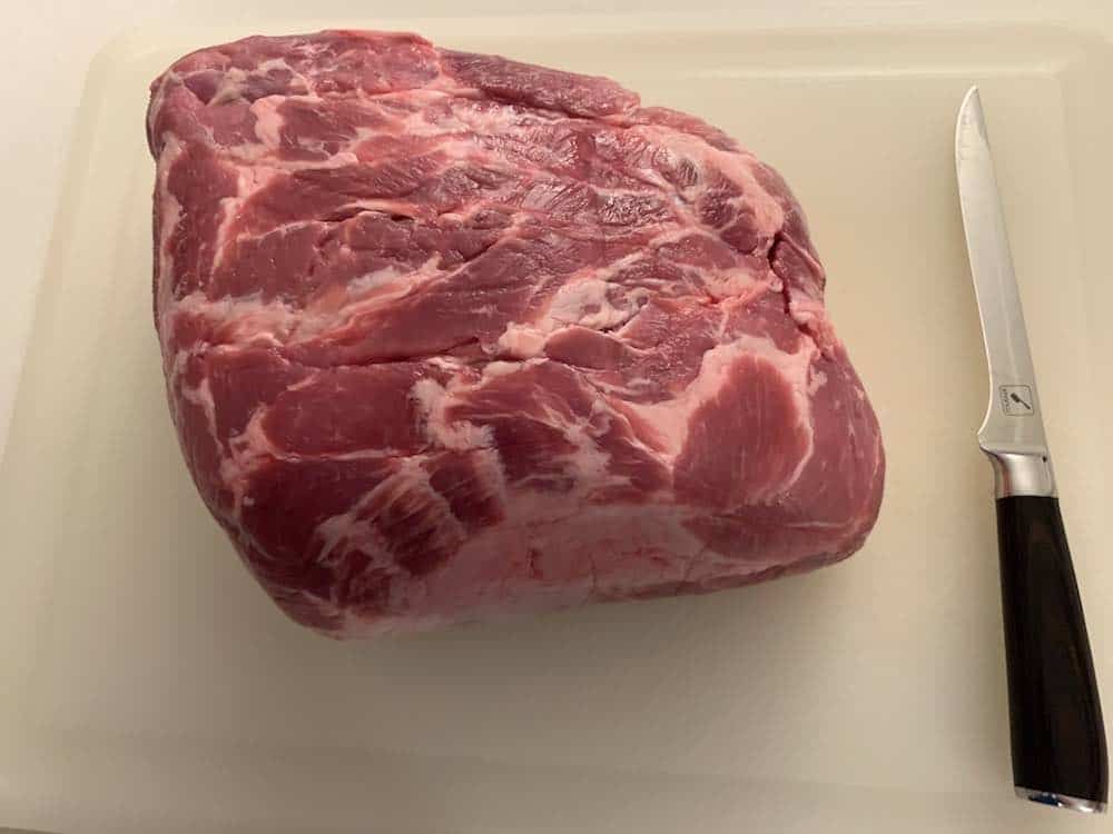 a raw pork butt on a cutting board