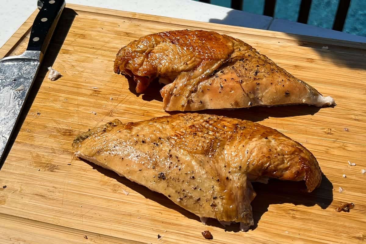 two intact turkey breasts on a cutting board