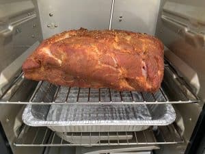 a pork butt with a temperature probe smoking in a masterbuilt electric smoker