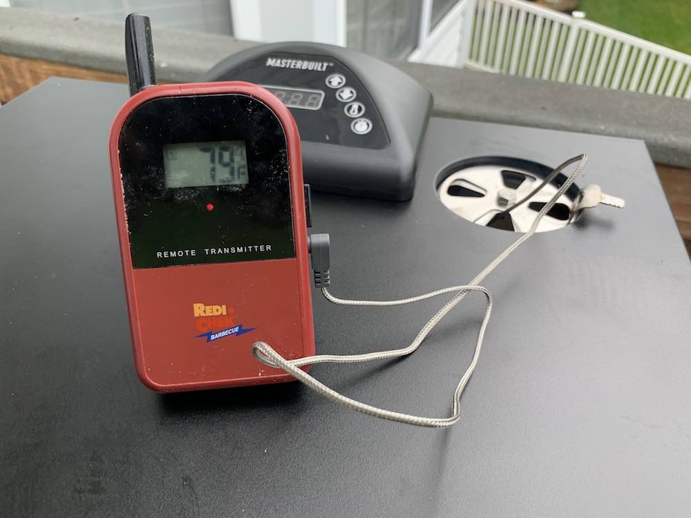 a leave in probe thermometer on top of a masterbuilt electric smoker