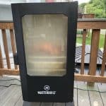 a masterbuilt electric smoker with the door closed full of smoke and a pork butt