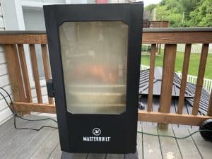 a masterbuilt electric smoker with the door closed full of smoke and a pork butt