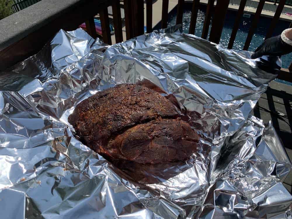 a smoked boston butt in foil about to be wrapped