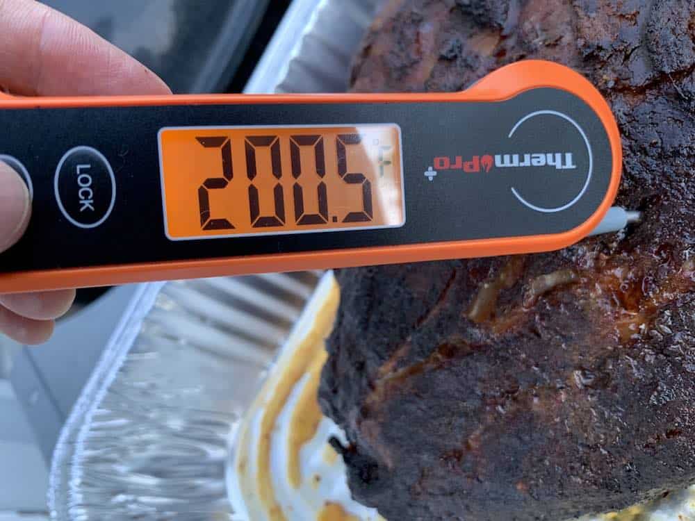 an instant thermometer reading 200 degrees on a smoked pork butt