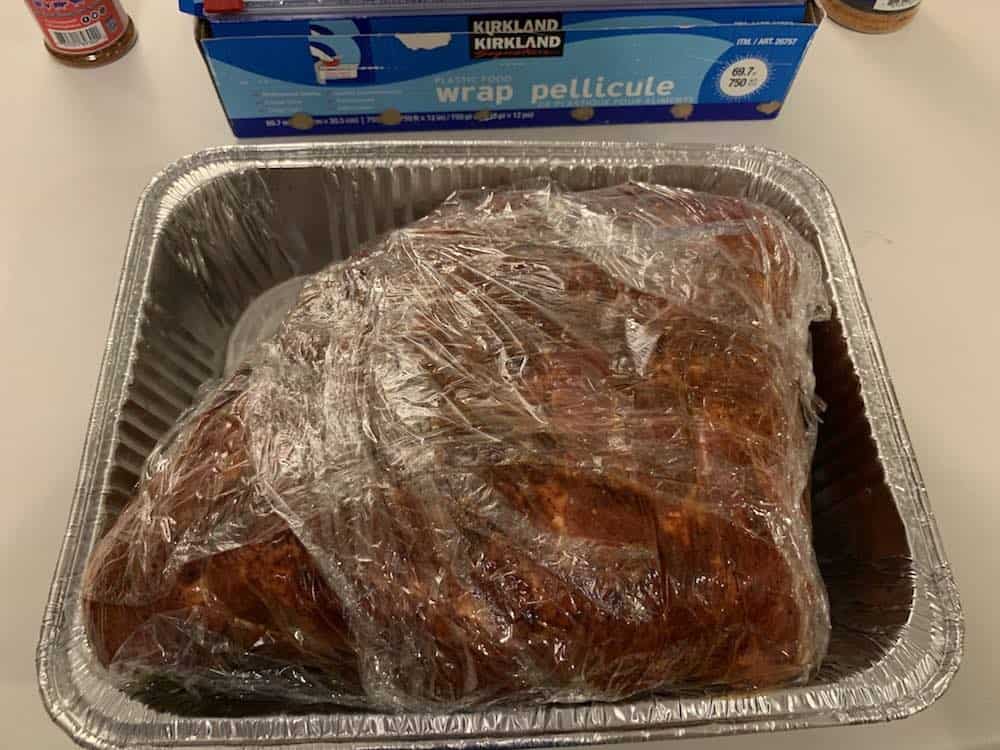 a seasoned pork butt wrapped in plastic wrap