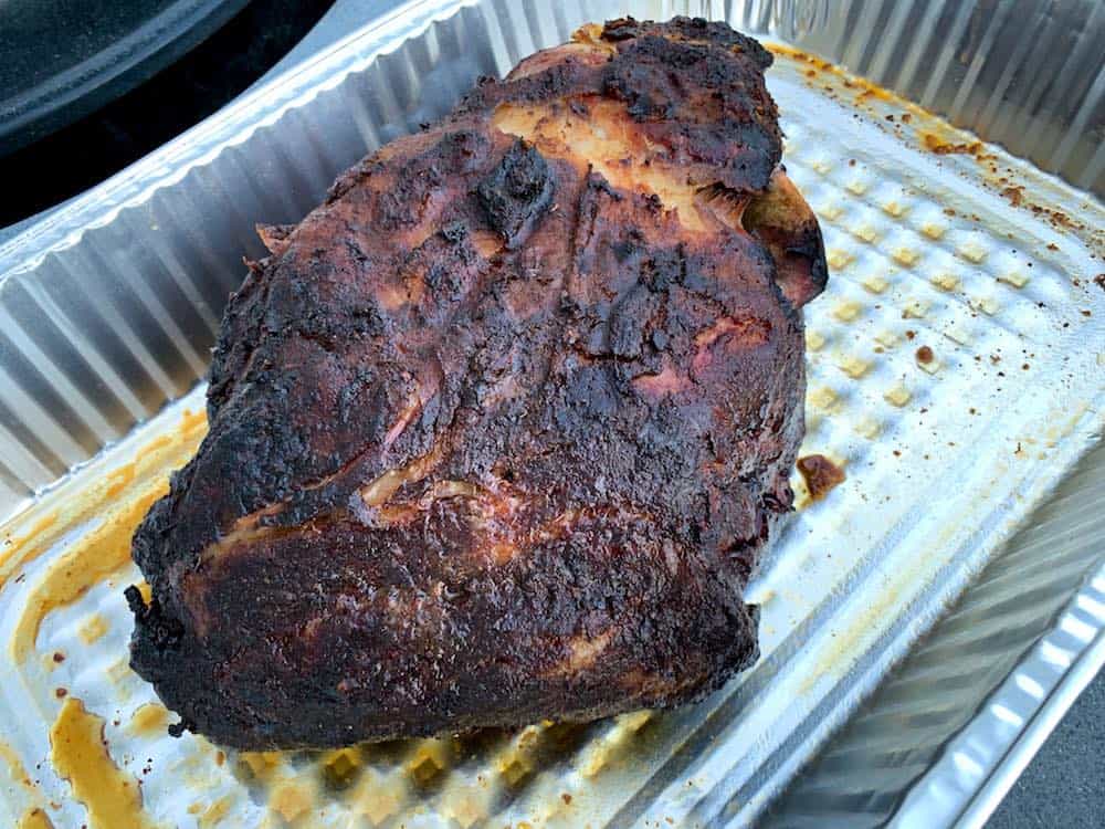 a finished smoked boston butt in a foil pan after coming out of an electric smoker