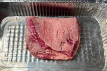 a raw corned beef brisket in an aluminum foil pan