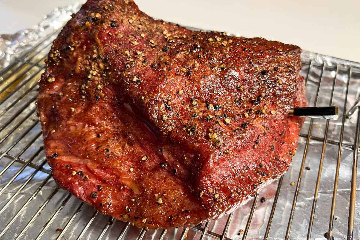 a corned beef brisket on a wire rack with a MEATER thermometer inserted into the center