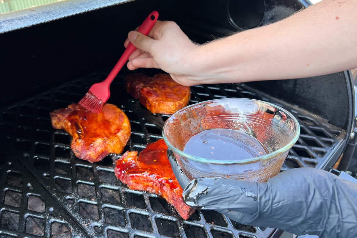 brushing pork chops with barbecue sauce using a silicone basting brush