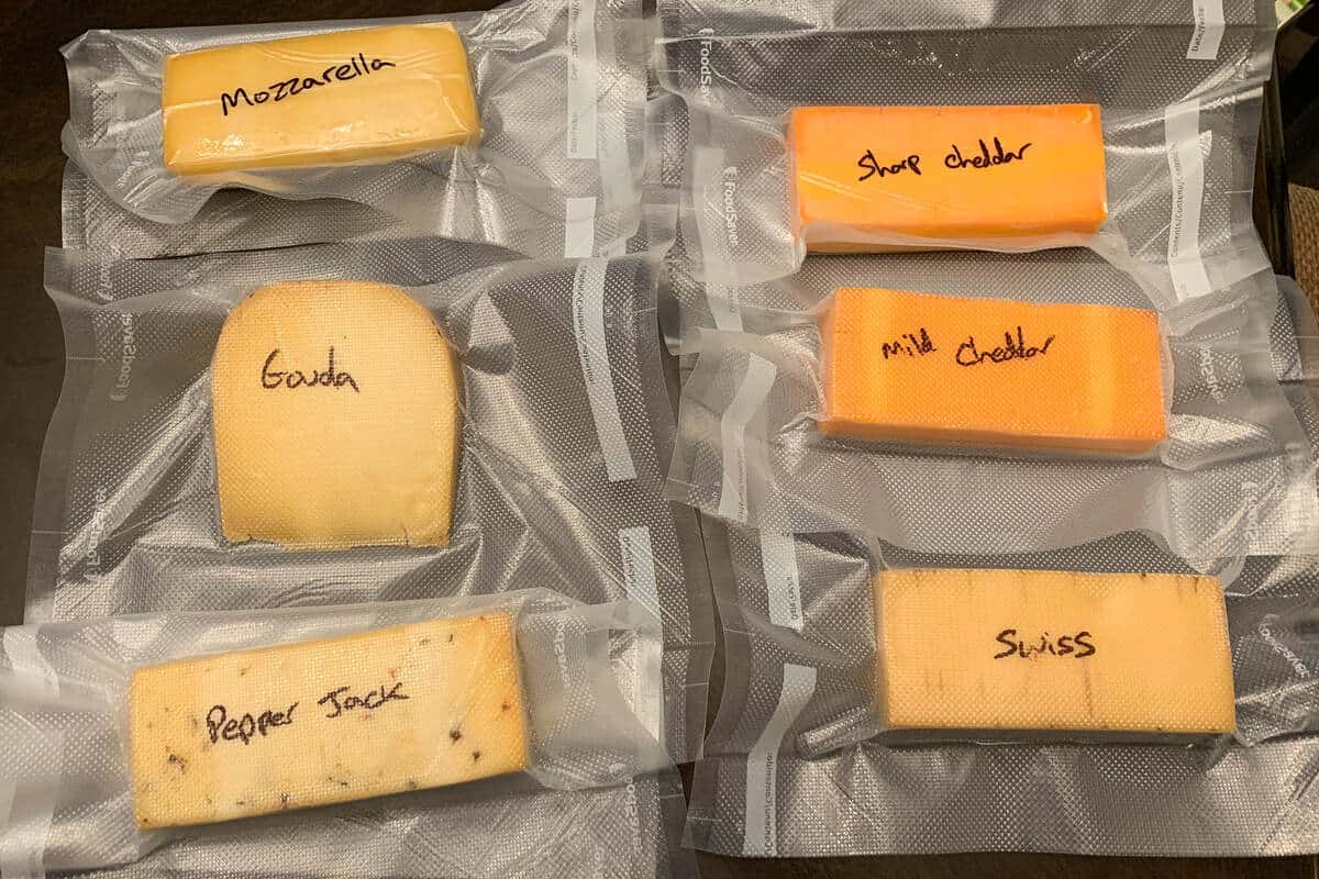 six blocks of cheese vacuum sealed in bags and labeled with a sharpie