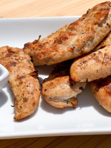 Smoked Chicken Tenders on a white plate with a bbq dipping sauce