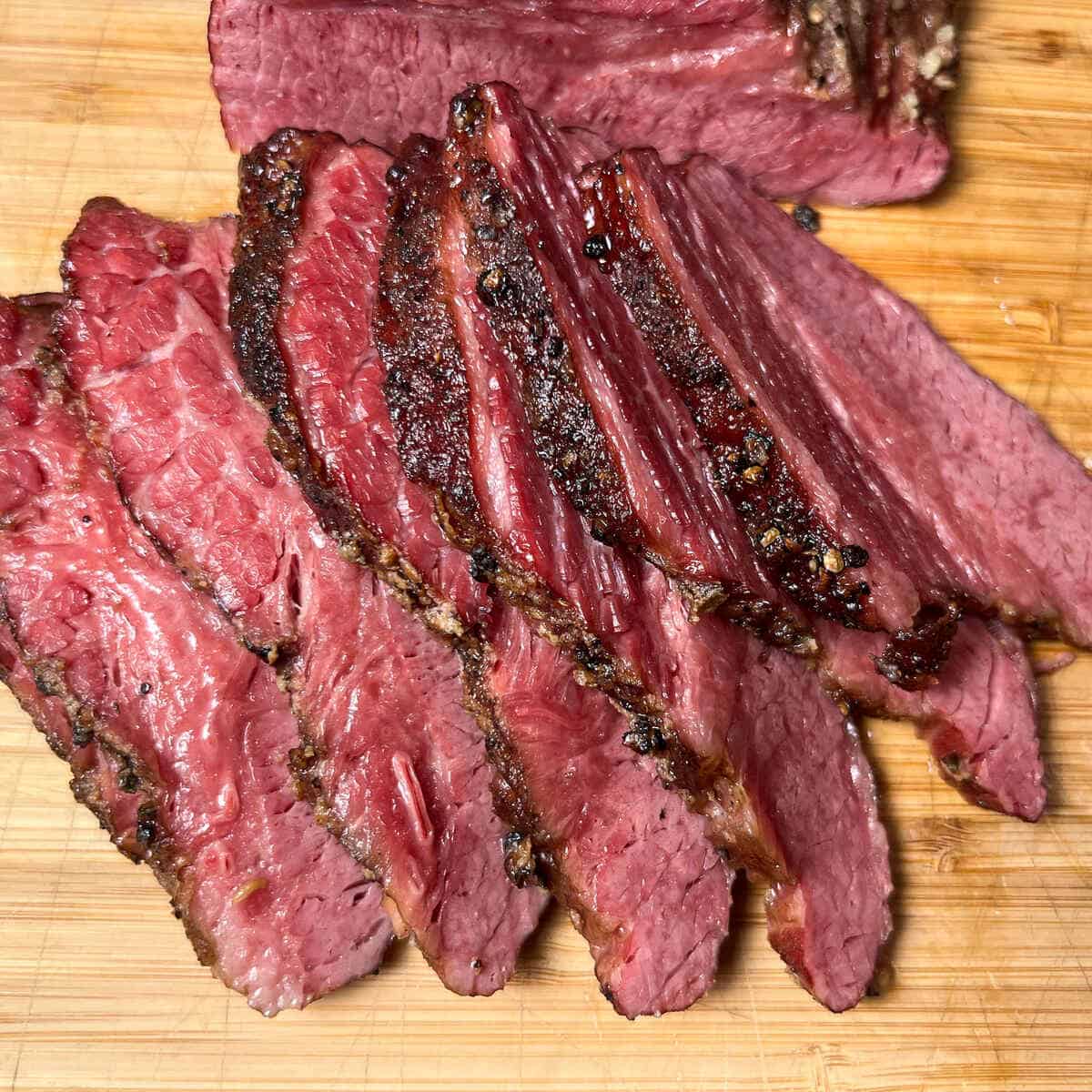 slices of smoked corned beef brisket on a wooden cutting board