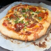 Smoked pizza on a piece of parchment inside a pellet grill