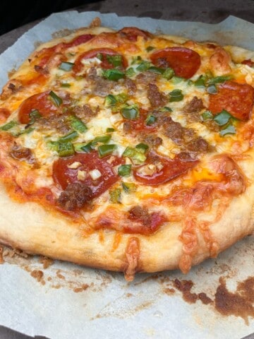 Smoked pizza on a piece of parchment inside a pellet grill