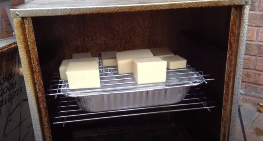 smoked cheese sitting on an ice tray in a masterbuilt electric smoker