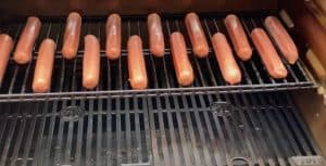 putting hot dogs on a smoker
