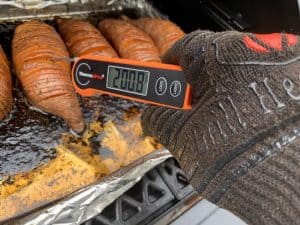 an instant thermometer showing 200°F on smoked sweet potatoes