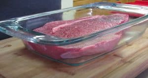 a raw london broil in a pyrex dish