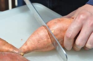 slicing a raw sweet potato