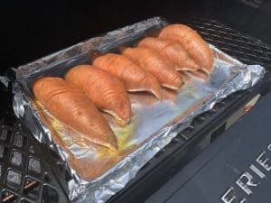a pan of sliced sweet potatoes going in a smoker