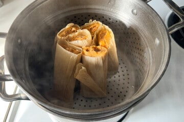 tamales placed upright in the steamer basket of a stockpot