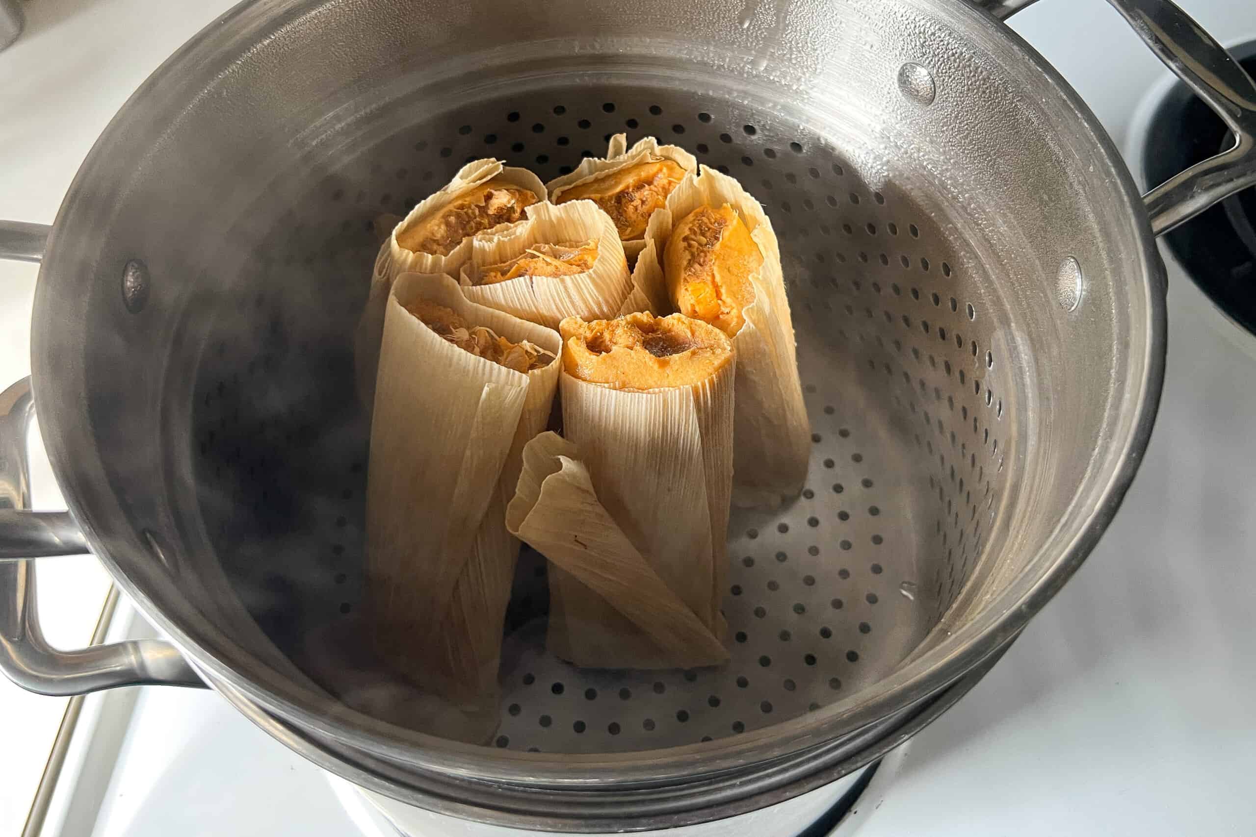 tamales placed upright in the steamer basket of a stockpot